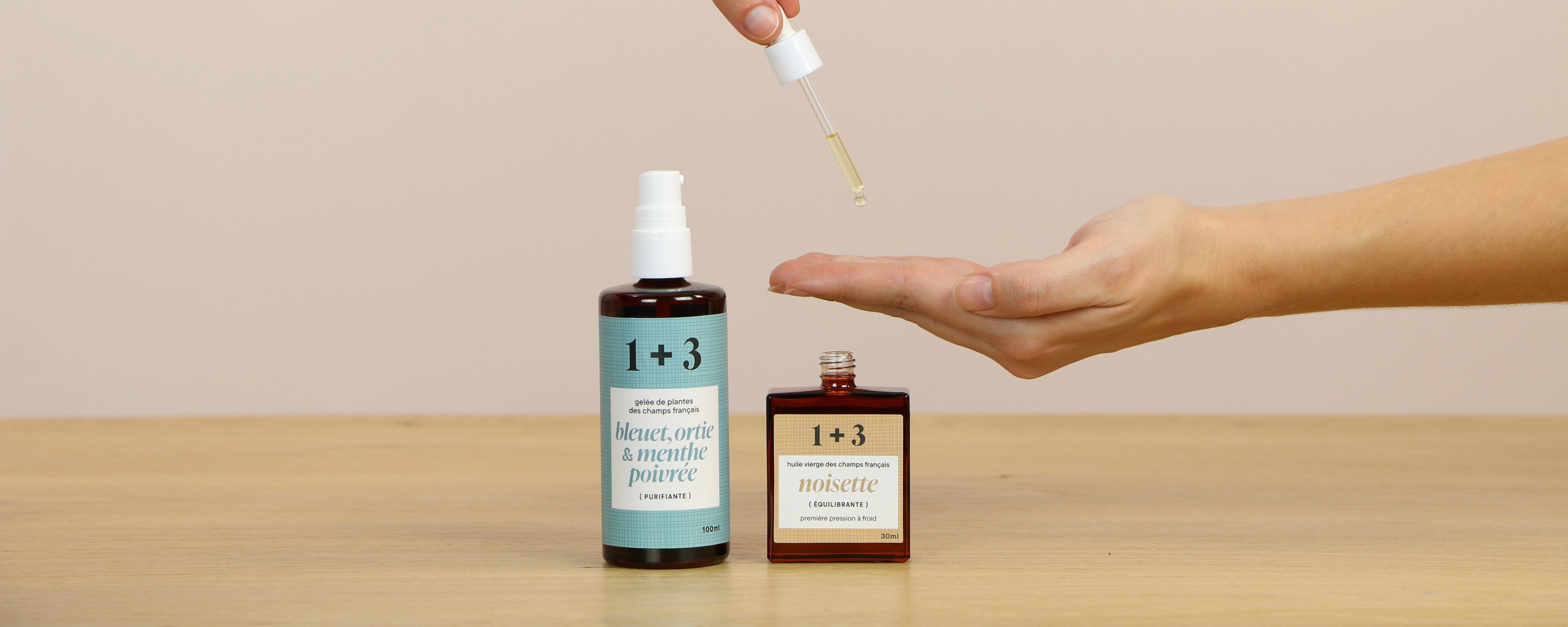 Main versant quelques gouttes d’huile de noisette 1+3 à l’aide d’une pipette, à côté d’une gelée purifiante bleuet, ortie et menthe poivrée – démonstration de la méthode 1+3
