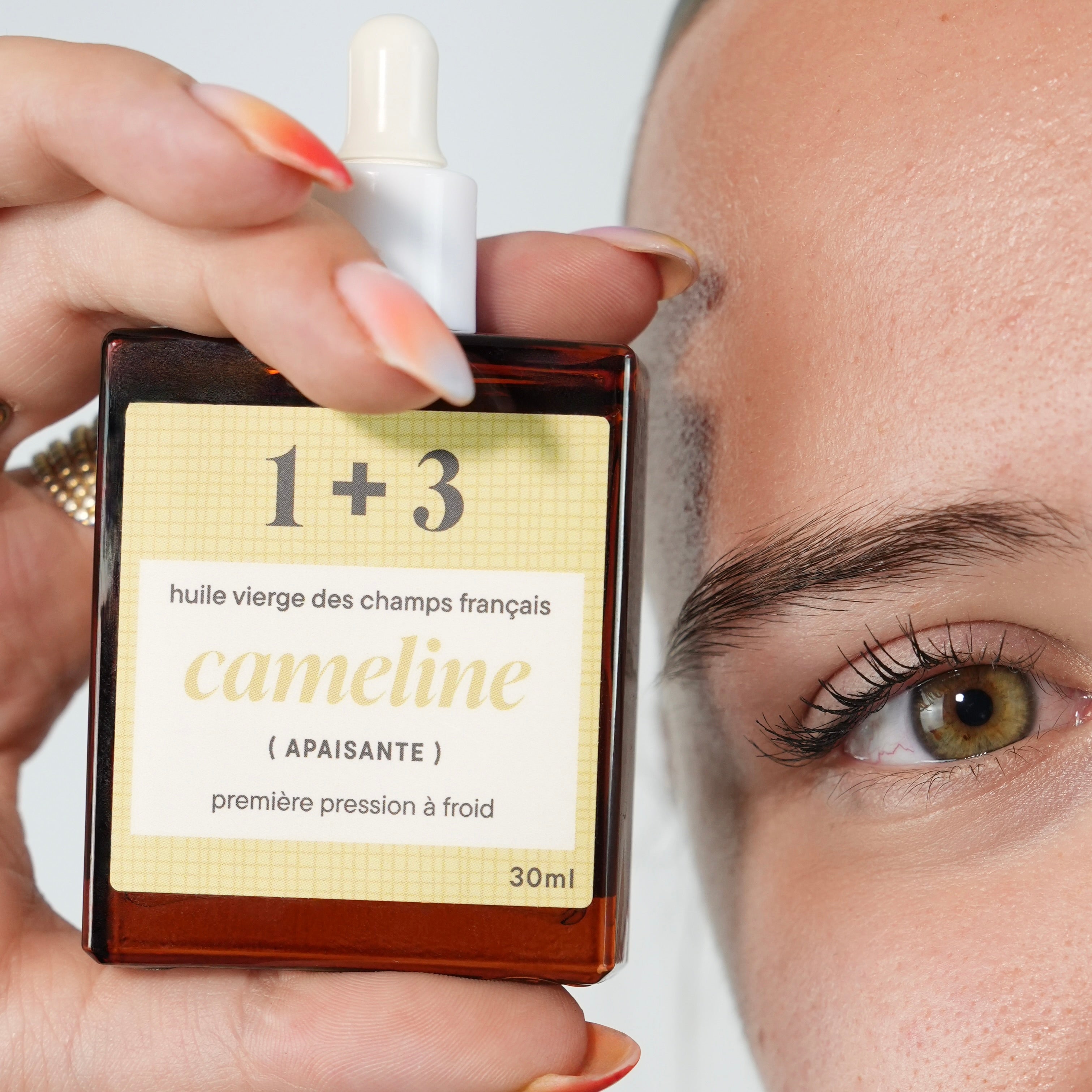 Gros plan sur l'huile de caméline à coté du visage de Marine.