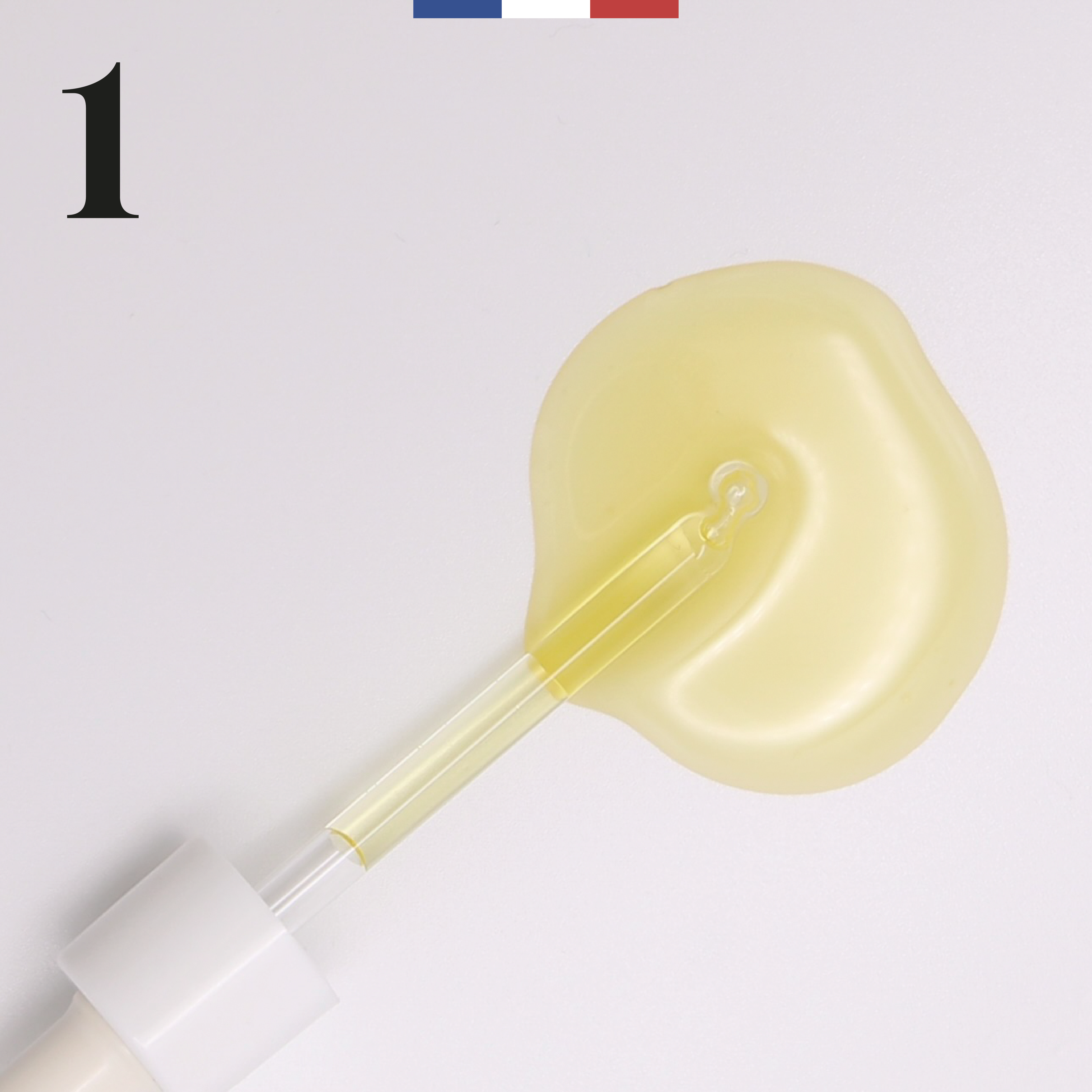 Goutte d’huile de noisette 1+3 – pipette déposant une huile dorée française équilibrante et légère sur fond blanc